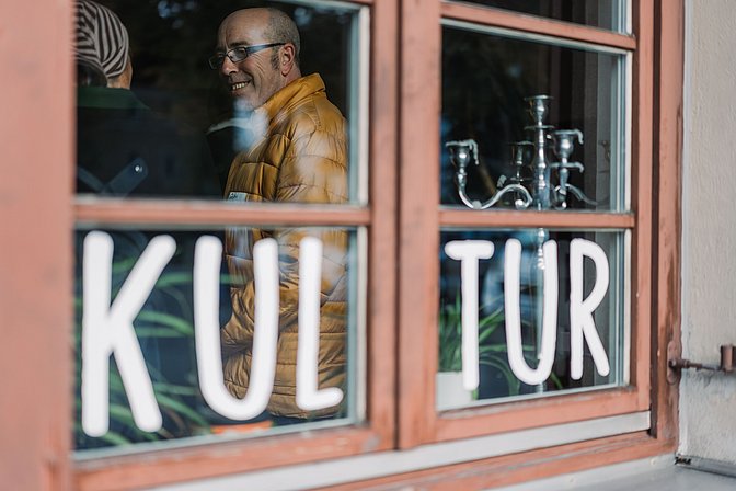 Durch das Fenster der Kulturwirtschaft in Kempten ist ein Gast zu sehen.