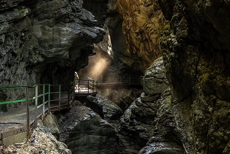 Steg entlang der Felswände der Breitachklamm, ein Sonnenstrahl erhellt die Schatten
