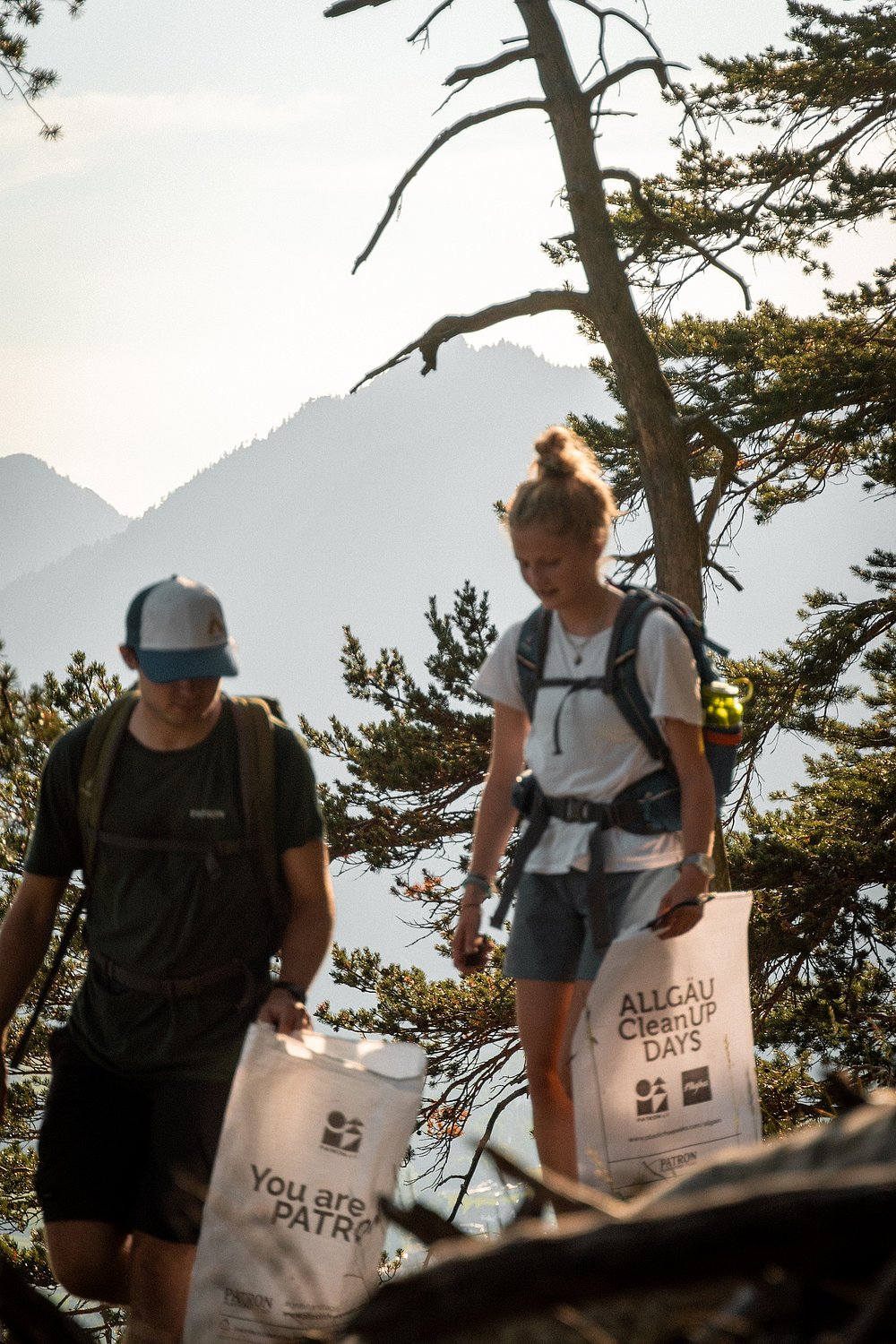 Ein Mann und eine Frau beim Wandern mit Mülltüten des Vereins Patron e.V.