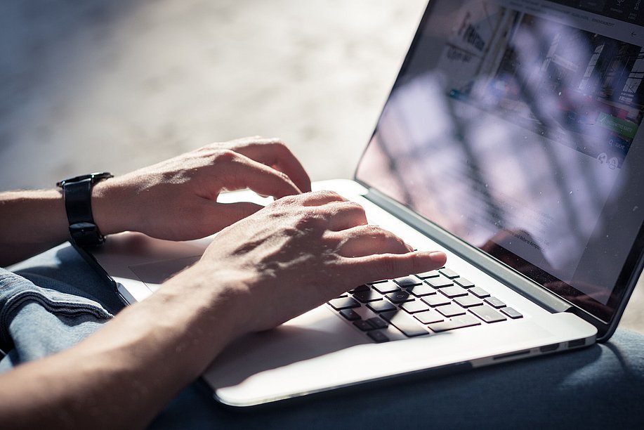 Laptop auf Schoß, Hände auf Tastatur