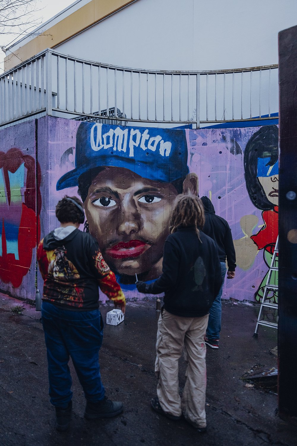 Drei Jugendliche vor einem frisch gesprayte Graffiti