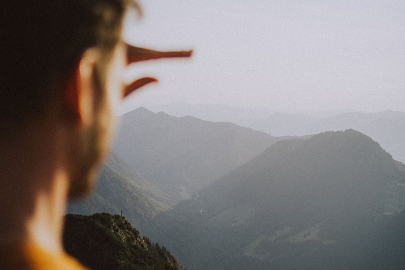Wanderer blickt am Iseler in die Ferne auf die Berge
