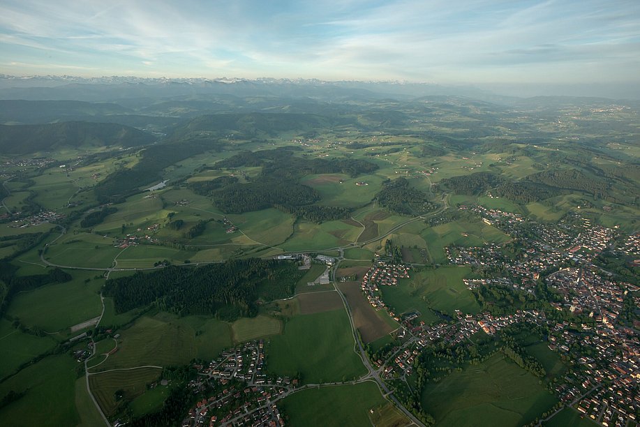 Luftaufnahme von Isny mit Hügeln und Alpenkette