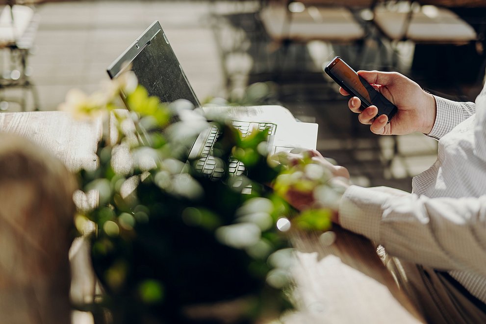 Arme eines Mannes an Laptop und Handy