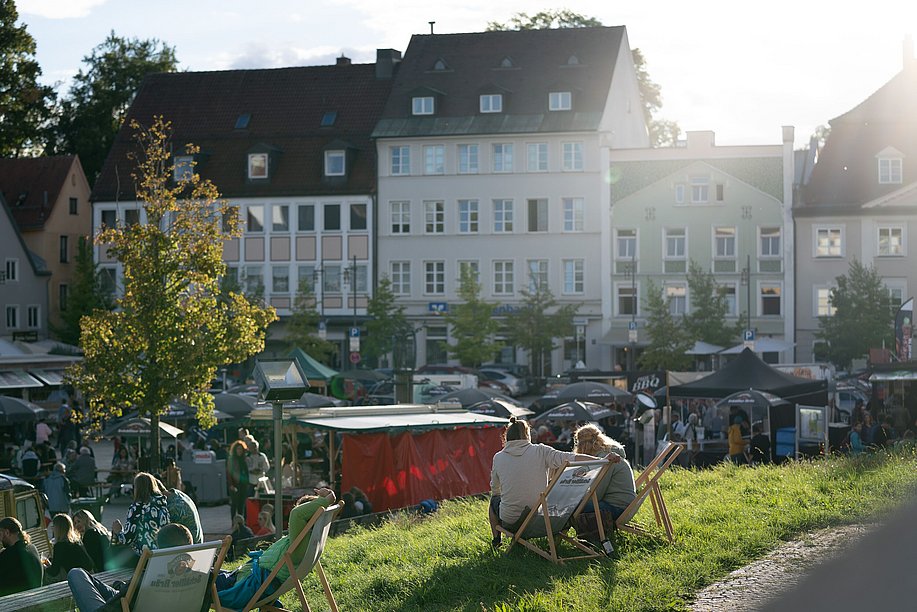 Besucher des Wochenmarktes in Kempten sitzen auf Liegestühlen in der Sonne