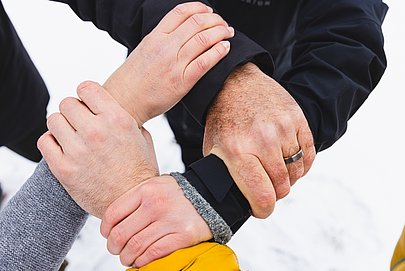 Vier Hände halten sich gegenseitig an den Handgelenken, sodass ein Kreis entsteht